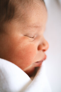 Newborn baby swaddled in white cloth, sleeping