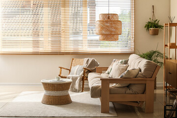 Interior of living room with comfortable sofa, coffee table, armchair and lamp