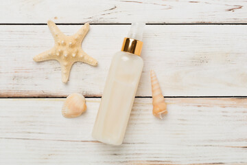 Sunscreen lotion with summer decor on wooden background, top view