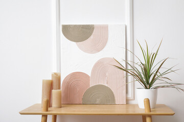 Shelving unit, houseplant and beautiful picture on white wall in room
