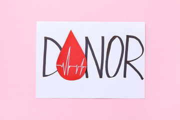 Paper sheet with text DONOR and blood drop on pink background. World Blood Donor Day
