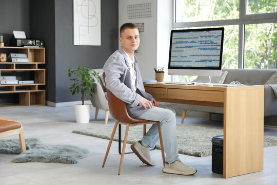 Young male programmer working with computer in modern home office