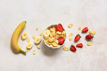 Banana, bowl with cornflakes and strawberries on light background