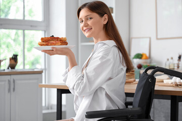 Young woman in wheelchair with tasty waffles at home