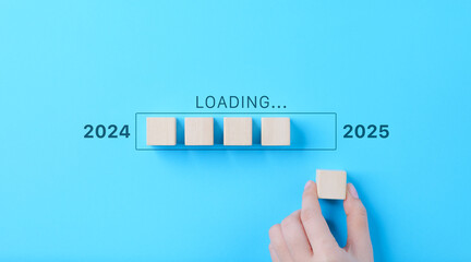 Loading Progress Bar from 2024 to 2025 with Wooden Blocks. A hand places wooden blocks in a row,...