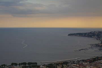 Yellow sunset over the bay and sea in Italy, view from above. Bay of Naples in the evening during sunset, panoramic view, Italian tourist walks around the city and small boat floating in the sea