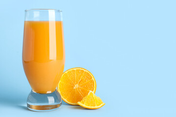 Glass of healthy orange juice on light blue background