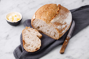 Rustic sourdough bread with cut slices on a marble table