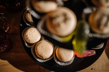 Dobele, Latvia - June 7, 2024 - Top view of beige macarons on a black tray, with red and green gummy candies, creating a visually appealing dessert display.