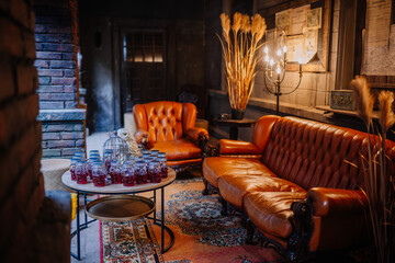 Dobele, Latvia - June 7, 2024 - Cozy vintage lounge with leather sofas, skull-shaped jars on a table, warm lighting, and rustic decor, creating an inviting ambiance. Copy space.