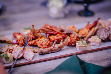 Dobele, Latvia - June 7, 2024 - Close-up of a gourmet appetizer platter with various meat dishes and garnishes on a wooden table, including slices and bone-in pieces. Copy space.