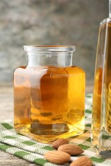Almond oil in bottle and nuts on table, closeup