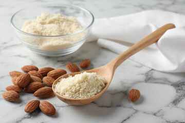Fresh almond flour and nuts on white marble table, closeup