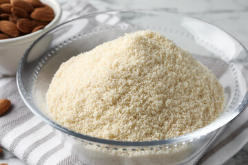 Fresh almond flour in bowl on white table, closeup
