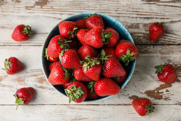 Bowl with sweet fresh strawberries on white wooden background