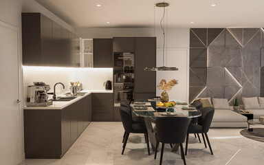 Modern kitchen and dining area featuring sleek dark cabinets, a glass dining table, and contemporary lighting. The open layout seamlessly connects to a stylish living room with geometric wall designs.