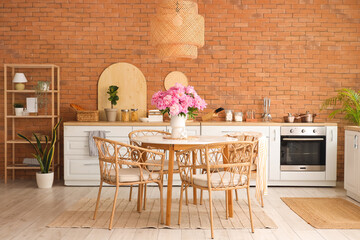 Vase with peonies flowers on dining table in kitchen