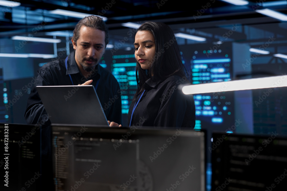 Poster programmers in server room checking recovery plan, monitoring tech gear energy consumption using not