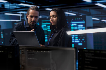 Programmers in server room checking recovery plan, monitoring tech gear energy consumption using...