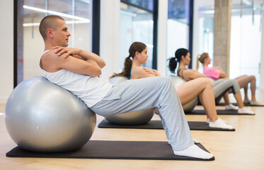 Obraz premium Four people lying on fitness balls and doing crunches