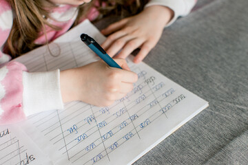 Girl's hands close up. School girl going homework at home, writing in notebook.