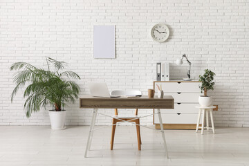 Interior of stylish office with workplace, laptop, chair and chest of drawers