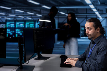 Software developer in server farm tasked to oversee supercomputers used for managing databases. IT expert in data center workspace location doing maintenance on rackmounts storing information