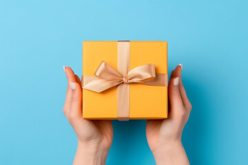 Yellow gift box held by hands on a blue background
