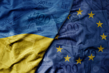 big waving realistic national colorful flag of european union and national flag of ukraine on a euro money banknotes background. © luzitanija