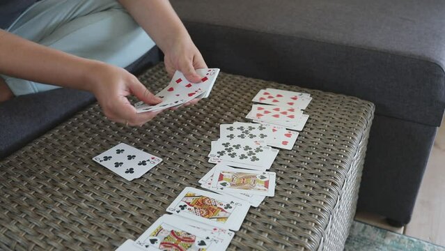 Woman Lays Out Playing Cards on Table Inside Home