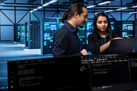 Software developers in data center running system diagnostic tests on laptop to fix problems. IT staff members deploying and error checking utilities on notebook to fix network issues performance