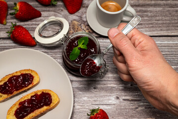 Man holding a teaspoon with strawberry jam. Delicious homemade strawberry jam, sweet and healthy breakfast.