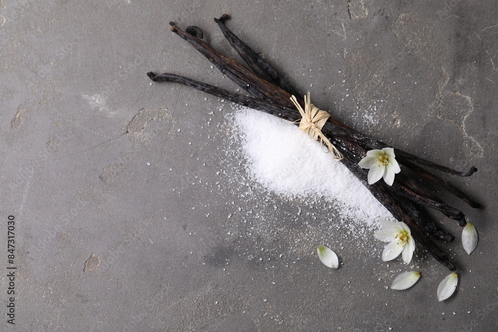 Wall mural Vanilla pods, sugar, flowers and petals on gray textured table, flat lay. Space for text - Wall murals