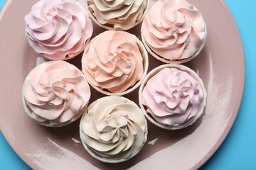Plate with tasty cupcakes on light blue background, top view
