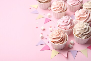 Delicious birthday cupcakes, bunting flags, marshmallows and sprinkles on pink background. Space for text