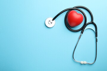 Stethoscope and red heart on light blue background, top view. Space for text