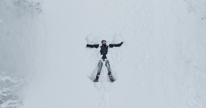 Man Creating Snow Angel Pattern In Fresh Snow