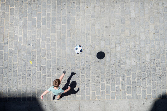 Child Playing Soccer in the Street in Seville, Spain