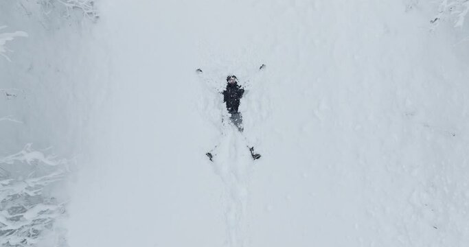 Top View Of Man In Black Jacket Making Snow Angel