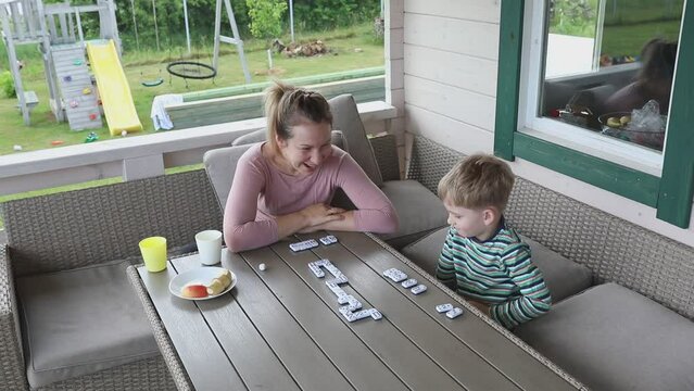 Mother and Sons Playing Dominoes on Terrace