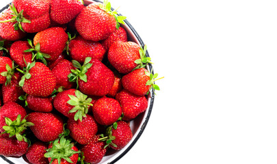 Close up of a whole red strawberry in a round bowl on a white background with space for text