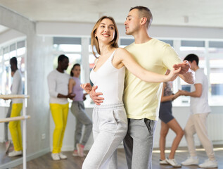 Young man and young woman dance ballroom dance waltz in studio