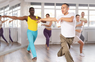 During dance workshop, European guy with team of like-minded multinational people learn to perform...