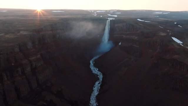 Aerial view of Hengifoss waterfall at sunset in Iceland, highlighting the dramatic landscape and natural beauty.