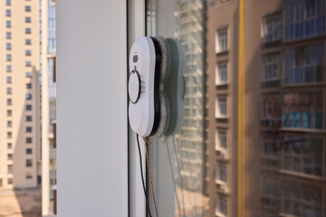 A robotic white Automotive tire is cleaning a glass window