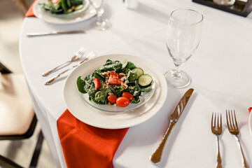 Salad with spinach, strawberries, cherry tomatoes, and cucumbers on a white plate.


