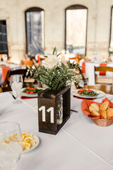 Table centerpiece with rose, greenery, table number 11, and bread basket.

