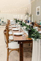 Elegant table setting with candles and greenery for an outdoor event

