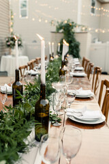 Elegant long table with greenery, candles, and place settings