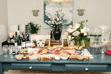 Dining table with charcuterie spread, flowers, and beverage dispensers